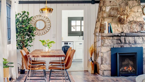 A dining area with a wooden table, leather chairs, and a hanging light fixture.