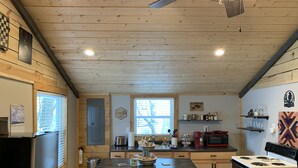 Una cocina acogedora con paredes de madera y una isla central, equipada con estufa, refrigerador y varios electrodomésticos.