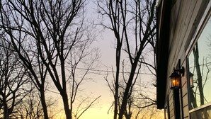 Una terraza de madera con una silla, una decoración de jirafa iluminada y vistas del atardecer.