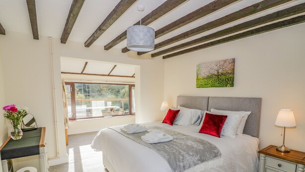 Een slaapkamer met een groot bed, een nachtkastje, een raam met uitzicht en een schilderij aan de muur.
