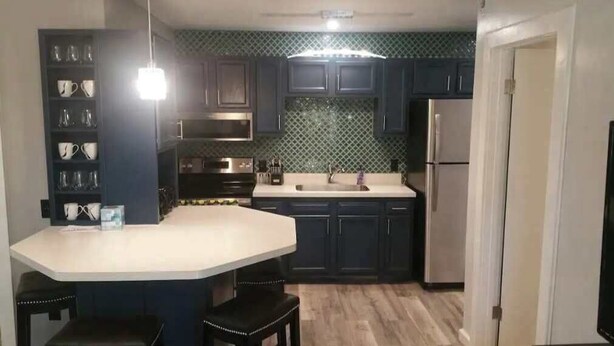 A modern kitchen with dark cabinets, a white countertop, and a built-in microwave.