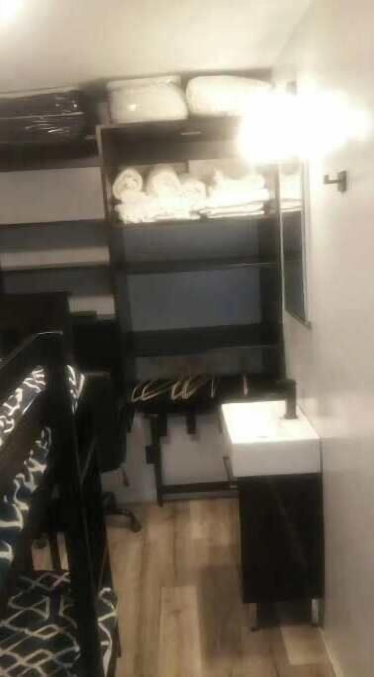 A compact room with a bunk bed, a desk, and a small bedside table.