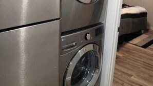 A compact kitchen with a stainless steel refrigerator and a built-in washer and dryer.