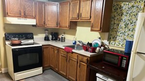 A kitchen with wooden cabinets, a stove, a microwave, and a refrigerator. - Rare 1 bedroom Gem (Wilmington)