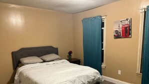A bedroom with a bed, a nightstand, a window with curtains, and a wall-mounted picture. - Rare 1 bedroom Gem (Wilmington)