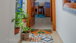 A hallway with a wooden door, a blue patterned window, and a potted plant. - Dar Jinane 2: Cosy and Stylish (Chefchaouen)