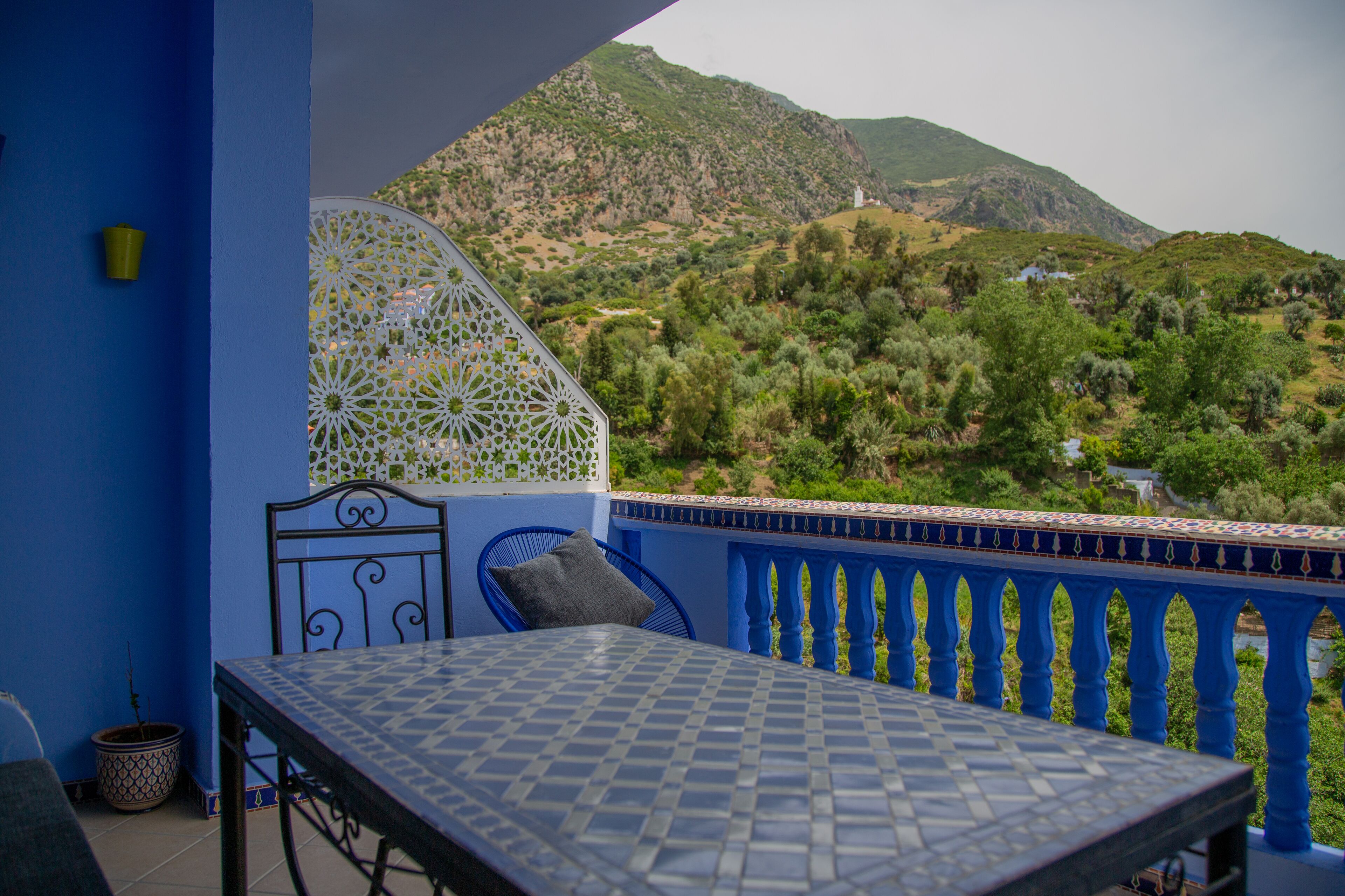 Ein Balkon mit Tisch und Stühlen, mit Blick auf eine gebirgige Landschaft.