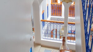 A staircase with a wooden handrail and blue metal railings, leading to a balcony with orange and white patterned railings. - Dar Jinane 2: Cosy and Stylish (Chefchaouen)