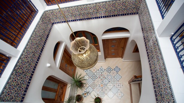 A courtyard with a hanging light fixture, tiled walls, and potted plants. - Dar Jinane 2: Cosy and Stylish (Chefchaouen)
