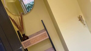 A hallway with a mirror, a wooden shelf with decorative items, and a door with a handle. - Hideaway 1-bed Apartment in Herne Bay (Herne Bay)