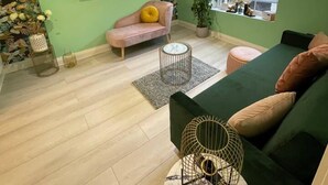 A modern living room with a green wall, a flat-screen TV, a sofa, a coffee table, and a potted plant. - Hideaway 1-bed Apartment in Herne Bay (Herne Bay)