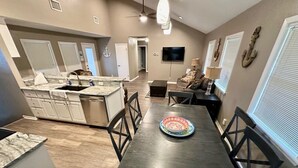 Une cuisine moderne avec un coin repas, comprenant un grand îlot central, une table en bois foncé et des chaises.