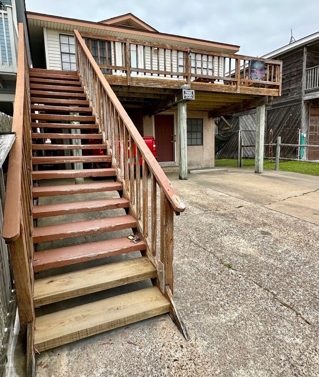 A wooden staircase leading to a building with a balcony.