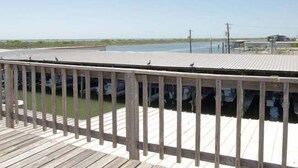 A wooden deck with a railing overlooking a body of water. - WATERFRONT Burnett House Up (Port O'Connor)