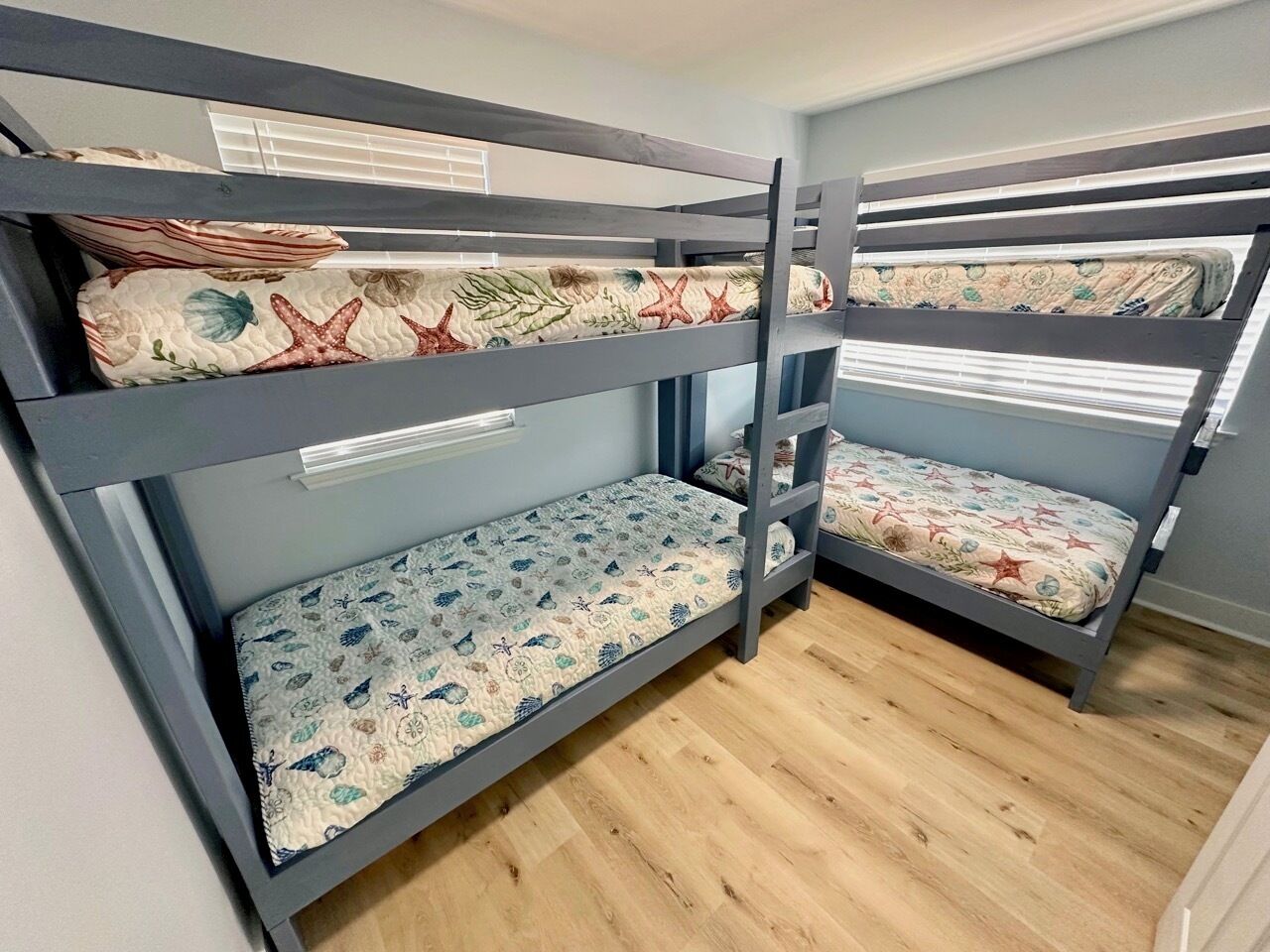 Habitación con literas de madera, dos literas y ropa de cama estampada.