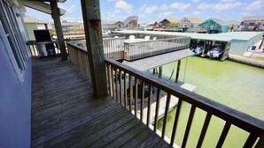 A wooden deck with a view of a marina and houses in the background.