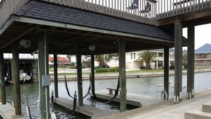A covered dock area with a wooden deck, water channels, and a small seating area.