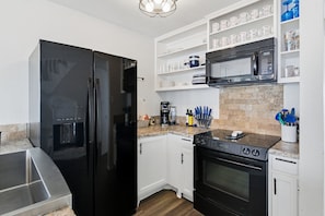 A modern kitchen with a black refrigerator, white cabinets, a microwave, and a stove. - WATERFRONT & PET FRIENDLY (adds fees) Dockside close to ICW (Port O'Connor)