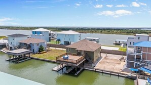 Una propiedad frente al agua con varias construcciones, incluyendo una casa con terraza y un muelle para barcos.