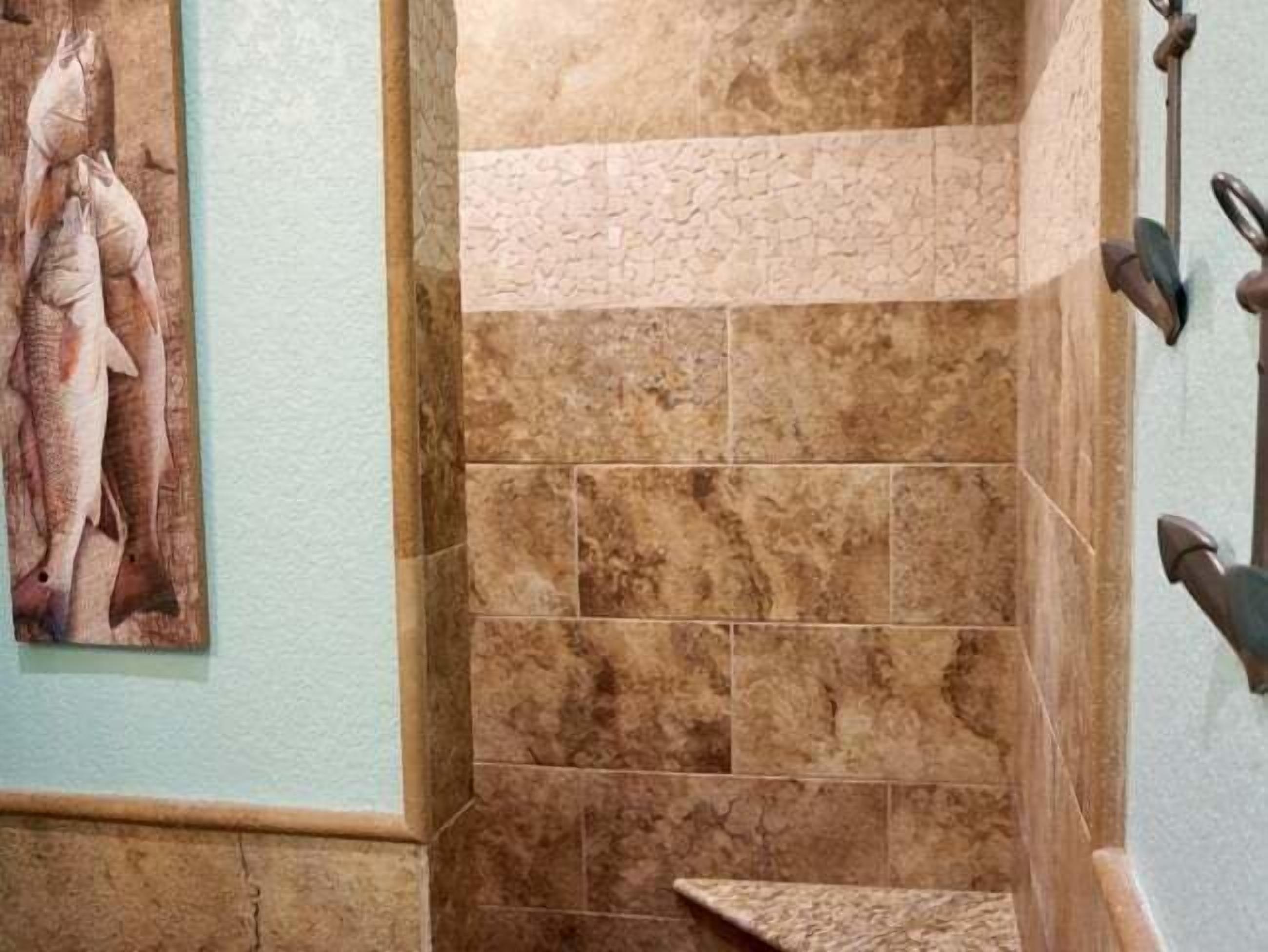 A bathroom with a tiled wall, a towel rack, and a framed picture of fish.