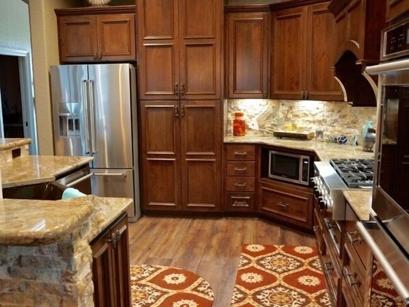 Una cocina con gabinetes de madera, un refrigerador de acero inoxidable, un microondas y una estufa.