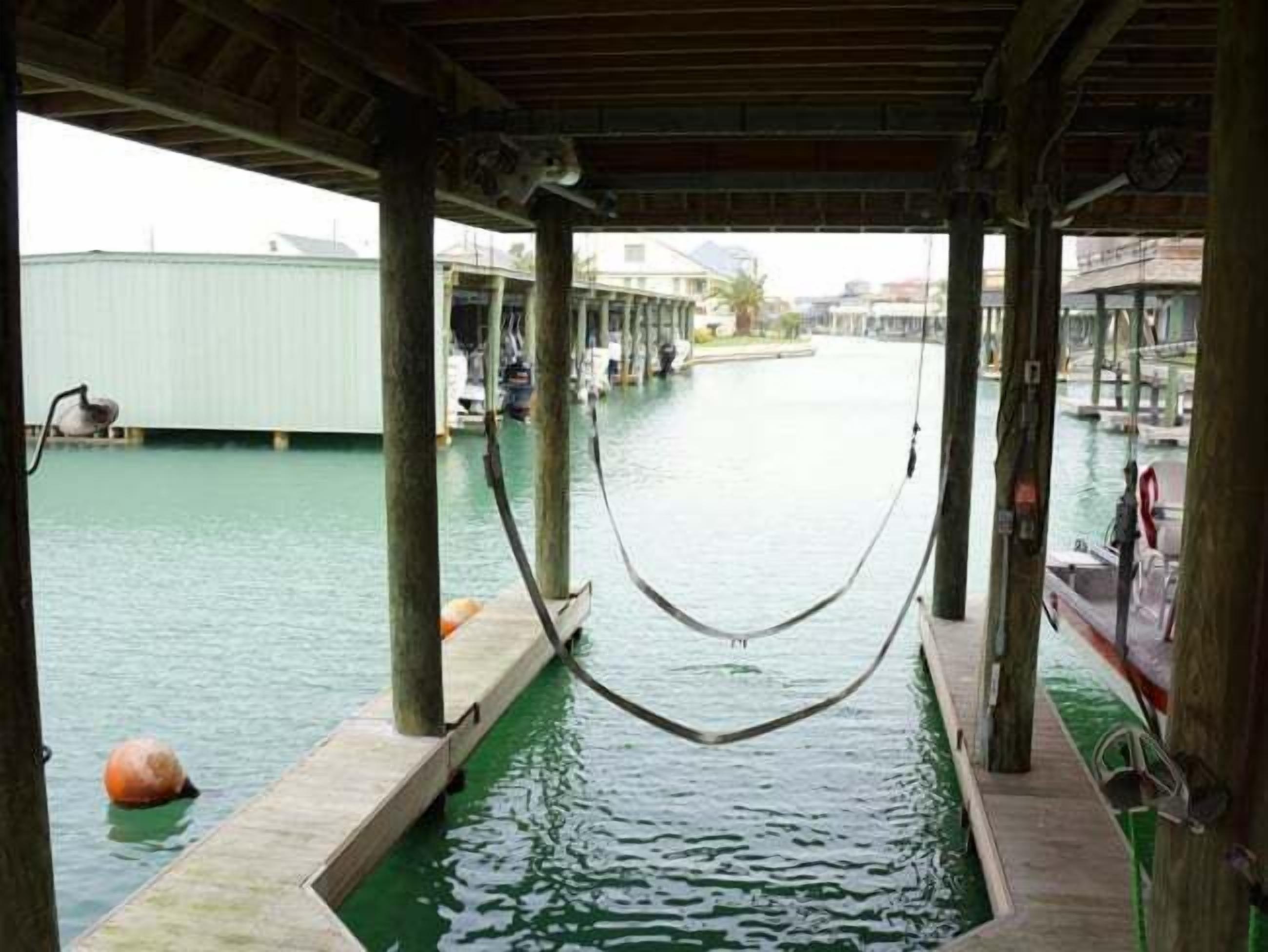 A covered waterway with a hammock hanging between wooden pillars.