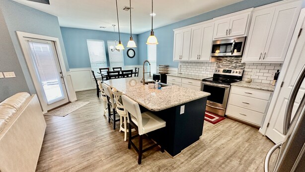A modern kitchen with white cabinets, a granite countertop, and stainless steel appliances. - PARKERSON HOUSE in Larry's Harbor POC (Port O'Connor)