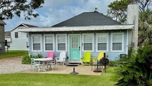 A house with a front porch, a dining table with chairs, and a small garden area. - SIREN COVE is Close to Beach in POC (Port O'Connor)