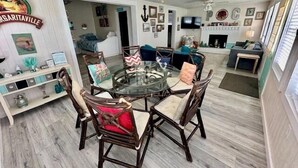 A dining area with a round glass table and wooden chairs, a ceiling fan, and a sign reading "Margaritaville". - SIREN COVE is Close to Beach in POC (Port O'Connor)