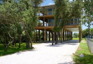 A multi-story building with balconies, supported by wooden pillars, surrounded by trees. - TEXAS TREEHOUSE is Close to Beach in POC (Port O'Connor)