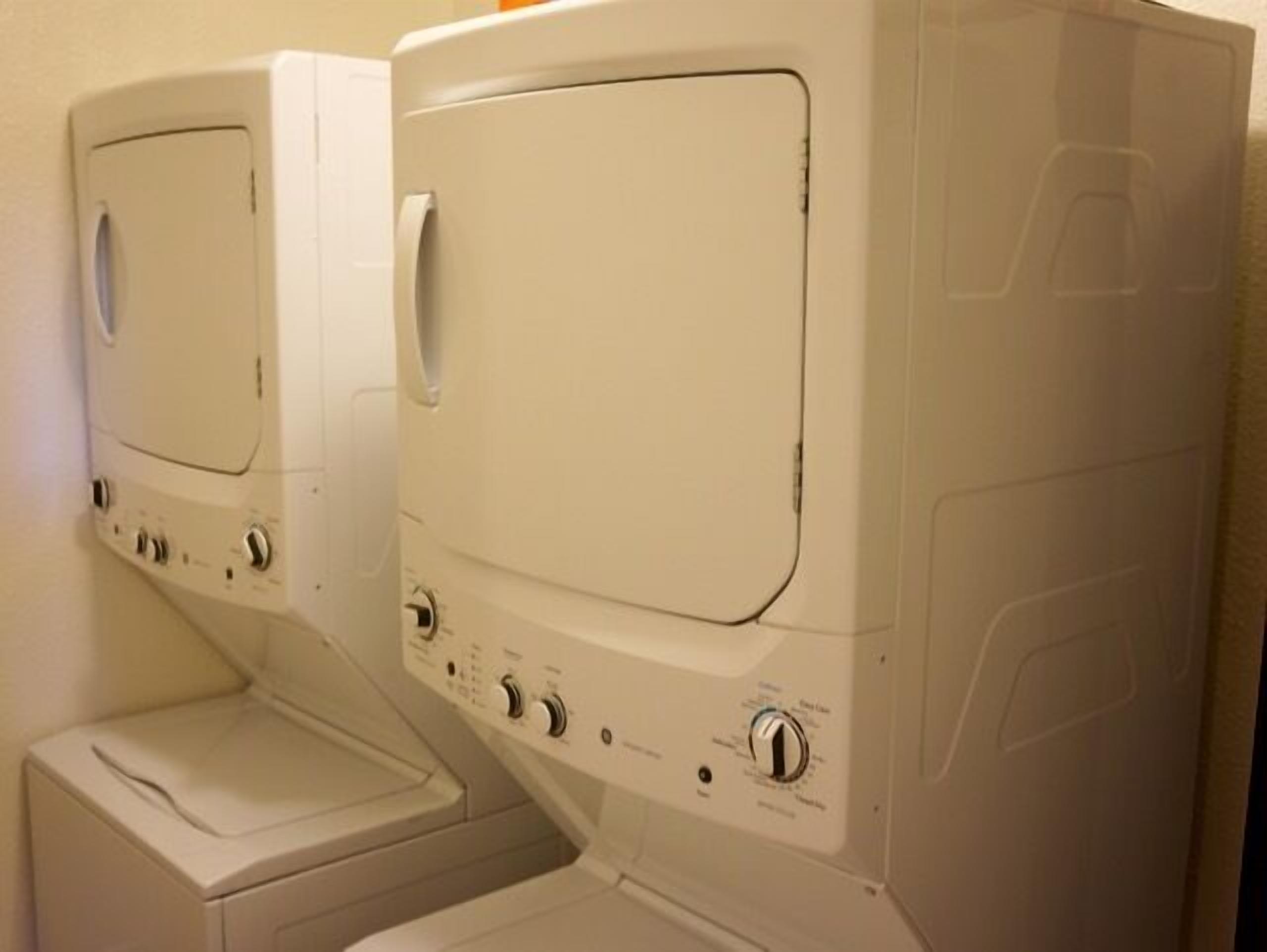 A laundry area with two stacked washing machines and a dryer.