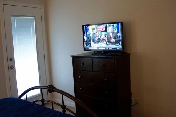 A bedroom with a bed, a dresser, and a television displaying a news program. - TEXAS TREEHOUSE is Close to Beach in POC (Port O'Connor)