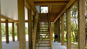 A wooden staircase leading up to an upper level with a view of trees. - TEXAS TREEHOUSE is Close to Beach in POC (Port O'Connor)