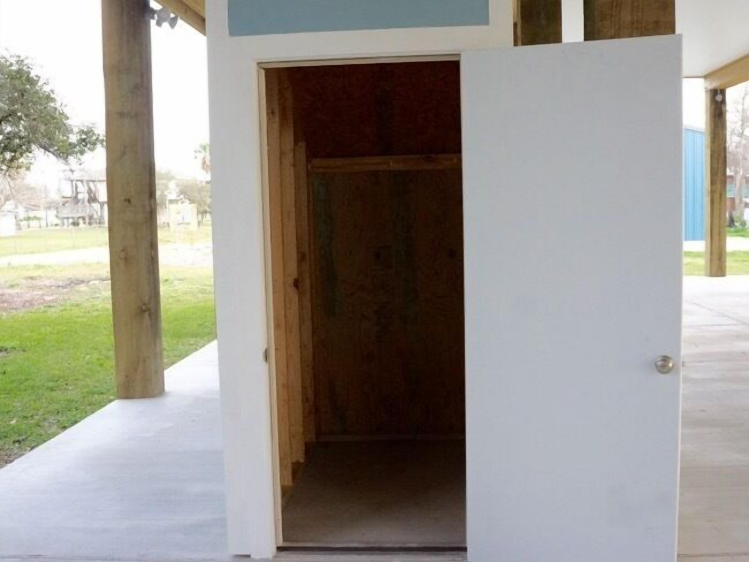 Une porte qui mène à une pièce aux murs en bois et au sol en béton.