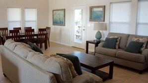 A living room with a sofa, coffee table, and a dining area with chairs and a table. - TEXAS TREEHOUSE is Close to Beach in POC (Port O'Connor)