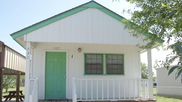 Un piccolo edificio a un piano, con una porta verde e pareti bianche.