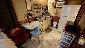 A compact kitchen with a stove, sink, and refrigerator. There is a small dining table with chairs.