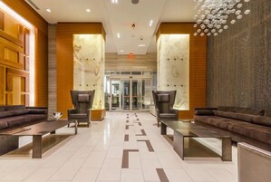 Een moderne lobby met een centrale zithoek, een glazen entree en een patroon vloer.