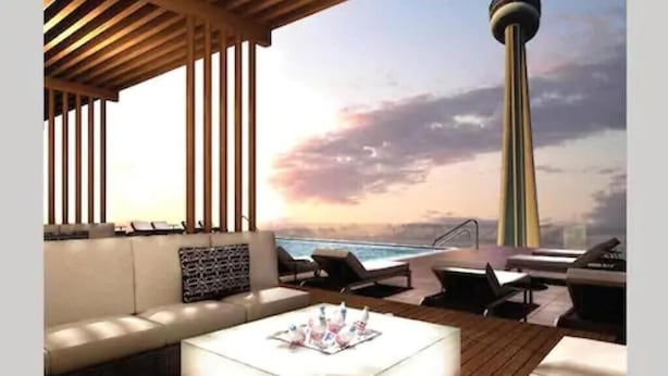 A modern outdoor seating area with a sofa and lounge chairs, a wooden deck, and a view of the ocean and a tower. - Skyline Suites - Next to MTCC, ACC & CN Tower (Toronto)