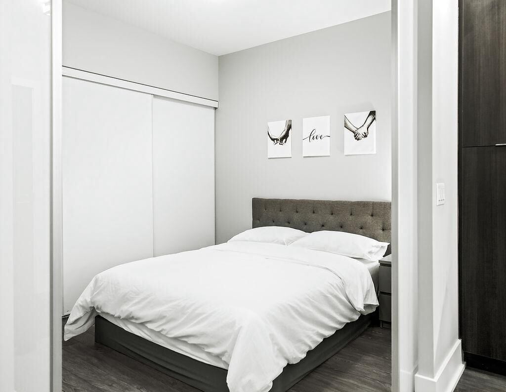 A bedroom with a bed, a wardrobe, and three framed pictures on the wall.