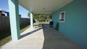 A covered patio area with a concrete floor, a wooden fence, and a blue wall. - UNCLE WOODY'S #1 in POC-Pets ok but add Fees (Port O'Connor)