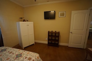 A bedroom with a bed, a wardrobe, a television, and a door.