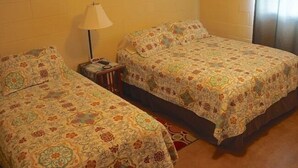 Una stanza accogliente e piccola con due letti singoli, un comodino, una lampada e un quadro appeso al muro.