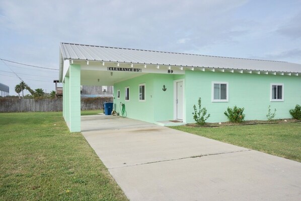 A single-story building with a light green exterior, a covered porch, and a clear sign indicating "CLEARANCE 85" and the number "89". - UNCLE WOODY'S #3 in POC-Pets ok but add Fees (Port O'Connor)