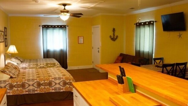 A hotel room with a bed, a desk, a chair, a ceiling fan, and a TV. - UNCLE WOODY'S #3 in POC-Pets ok but add Fees (Port O'Connor)