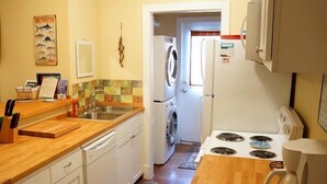 A compact kitchen with white cabinets, a wooden countertop, a stove, a sink, and a coffee maker. - UNCLE WOODY'S #3 in POC-Pets ok but add Fees (Port O'Connor)