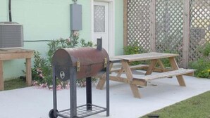 A barbecue grill with wheels, a picnic table, and a small outdoor area with a fence. - UNCLE WOODY'S #4 in POC-Pets ok but add Fees (Port O'Connor)