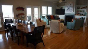 A spacious living room with a wooden dining table, chairs, a sofa, and a TV.