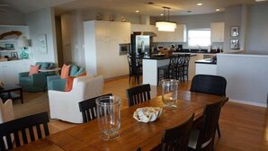 A modern kitchen with white cabinets, a central island, and a dining area with a wooden table and chairs.