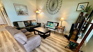 Una sala de estar con sofá, mesa de centro y mueble para televisión.